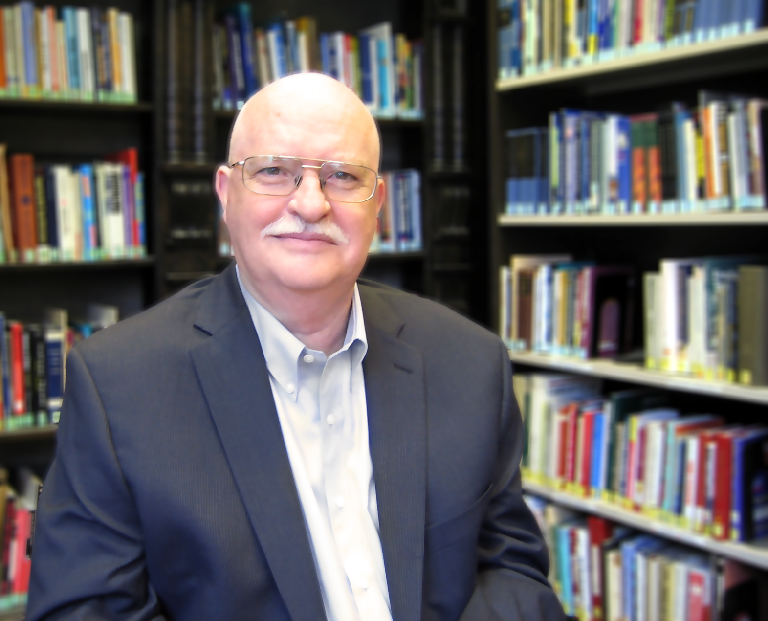 Photo of Chris Schenk in front of bookcases