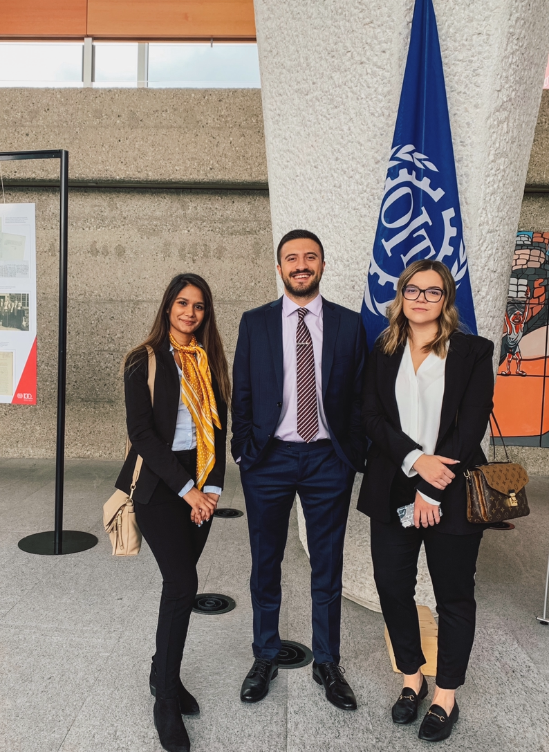 Photo of three people in front of a flag