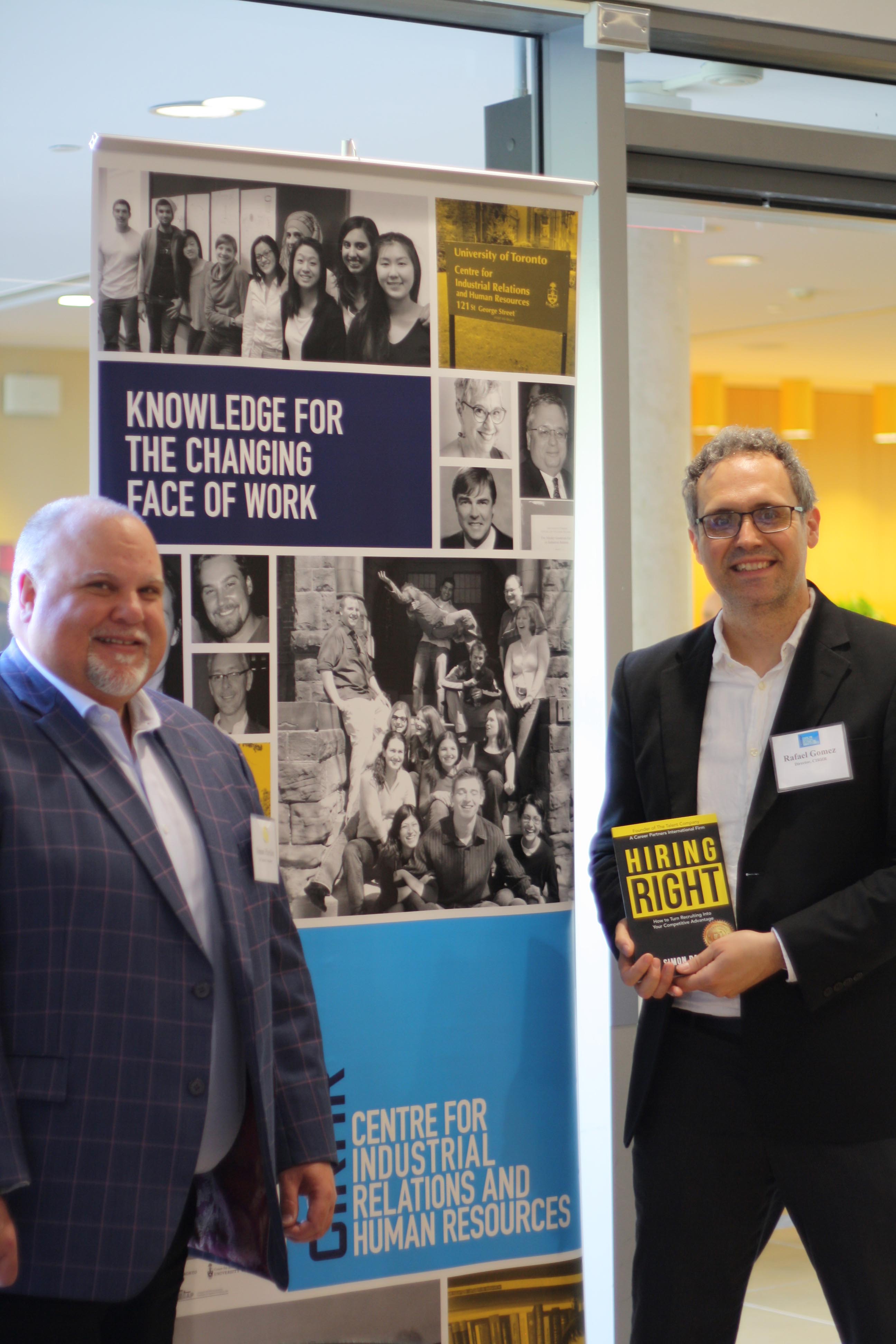 Simon Parkin (left) and Rafael Gomez pose with Parkin's book and the CIRHR banner