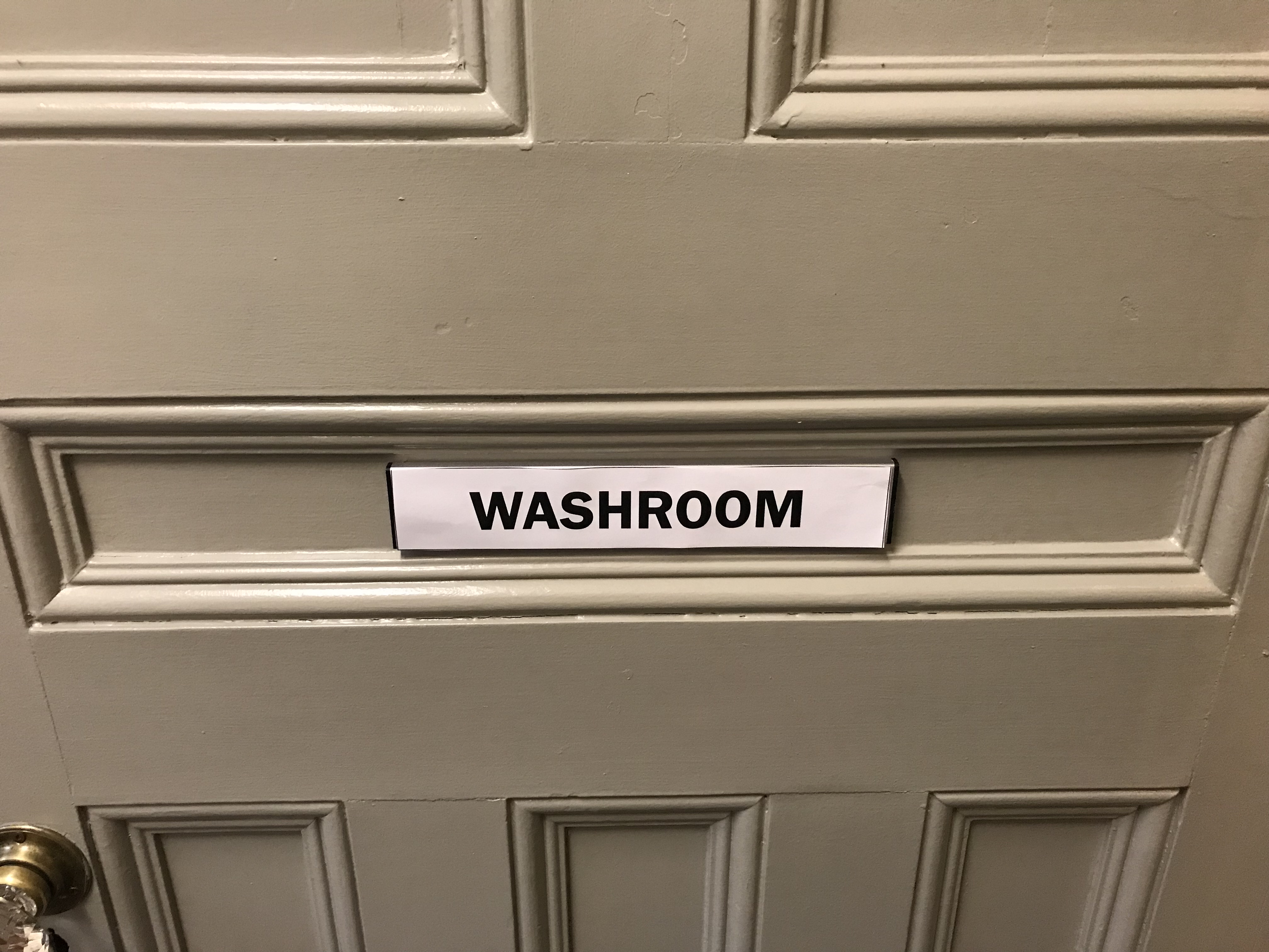 Photo of a door with a paper sign reading "washroom"