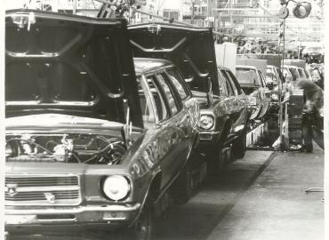 Black and white archival photo of cars on an assembly line